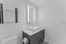 Floating vanity with a solid-surface countertop and rectangular vessel sink, integrated LED mirror, and wall-mounted glass shelving