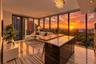 Floor-to-ceiling glass walls with sunset backdrop, kitchen island with stone-finish countertop and wood-finish cabinetry, linear stone-finish flooring