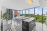 Floor-to-ceiling glass windows, kitchen island featuring a stone-finish countertop with a wood-finish breakfast bar, polished stone-finish flooring, a