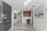 Glossy charcoal cabinetry, wood-finish wall-mounted cabinetry, and large-format tile flooring