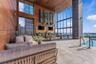 Outdoor lounge featuring wood-paneled walls and ceiling, floor-to-ceiling glass windows, stone-tiled flooring, and a recessed swimming pool with metal