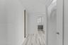 Hallway featuring linear-patterned tile flooring, a louvered white door with satin hardware, recessed ceiling lighting, and a flush-mounted wall mirro