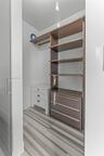 Walk-in storage space featuring wood-finish open shelving, built-in lower drawers, and tile flooring