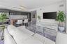 Kitchen featuring high-gloss cabinetry, stone backsplash, and an integrated wood-finish breakfast bar, complemented by polished stone-finish flooring 