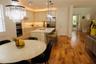 Kitchen featuring light-toned cabinetry, a center island with a stone countertop, wood-finish flooring, stainless steel built-in double wall ovens, an