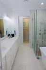 Dual-sink vanity with a solid-surface countertop, glass-enclosed walk-in shower with multi-head fixtures, freestanding soaking tub with floor-mounted 