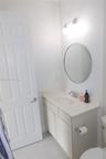 Bathroom featuring a vanity with a white solid-surface countertop, an integrated sink, polished chrome faucet, circular wall mirror, and dual-bulb van