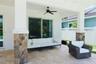 Covered patio featuring stone-clad pillars, natural stone flooring, and a ceiling-mounted fan