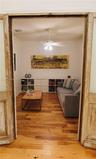 Interior room featuring wood-finish flooring, a ceiling fan with integrated lighting, and built-in white shelving