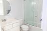 Bathroom featuring a vanity with an integrated sink and chrome faucet, circular wall mirror, and a tub-shower combination enclosed by sliding glass do