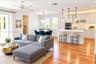 Open-concept interior featuring wood-finish flooring, white cabinetry, an island with stone countertop, stainless steel double wall ovens, and decorat