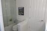 Bathroom featuring a glass shower panel, tub with tiled surround, and a white interior door with brushed metal hardware
