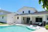 Swimming pool with a baja shelf, covered patio with ceiling fans, stone-pillar accents, and exterior light fixtures