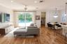 Open-concept living space featuring wood-finish flooring, recessed lighting, a ceiling fan, sliding glass doors, and a multi-tiered crystal pendant li