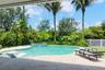 Backyard swimming pool with an integrated spa, tiled pool deck, palm trees, and perimeter fencing