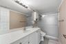 Bathroom featuring a white vanity with an integrated basin, a full-width wall mirror, an overhead multi-light fixture, built-in upper cabinetry, and a