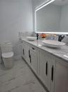Double vanity with stone-finish countertop, dual vessel sinks, matte black fixtures, LED-integrated mirror, and large-format porcelain tile flooring