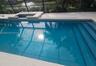 Screened-in pool area featuring an integrated spa, tiled waterline finish, and concrete pool deck