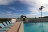 In-ground swimming pool featuring a brick paver deck, perimeter wall, gated access, and integrated metal pool ladder