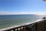 Elevated balcony featuring a metal railing overlooking the ocean coastline and sandy beach
