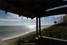 Covered wooden deck featuring exposed rafters and balustrade, positioned directly above the shoreline with ocean access