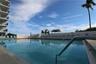 In-ground swimming pool with tile surround, concrete decking, metal safety handrails, and perimeter privacy wall