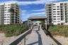 Elevated wooden boardwalk featuring a covered gazebo, built-in benches, and direct path toward multi-story residential buildings