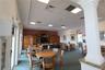 Open-concept common area featuring a dropped tile ceiling with recessed lighting, integrated wood cabinetry, a decorative column, and natural stone-su