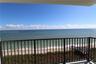 Covered balcony featuring metal railings with direct ocean and sandy beach exposure