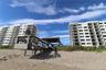 Exterior view of multi-story buildings featuring private balconies and a wooden boardwalk with a covered gazebo structure situated on sandy beach terr
