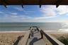 Covered wooden deck featuring a direct staircase leading to a private sandy beach