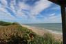 Direct oceanfront property featuring a sandy beach, shoreline vegetation, and open horizon