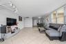 Open-concept interior featuring large-format diagonal tile flooring, crown molding, multi-arm arched floor lighting, and expansive windows with horizo