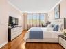 Room featuring polished wood-finish flooring, crown molding, and large windows with horizontal blinds