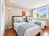 Bedroom featuring wood-finish flooring, recessed ceiling detail, and large windows with horizontal blinds