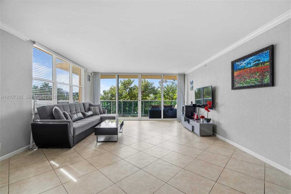 Living area featuring large-format diagonal tile flooring, floor-to-ceiling glass sliding doors, and crown molding
