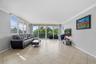 Living area featuring large-format diagonal tile flooring, floor-to-ceiling glass sliding doors, and crown molding