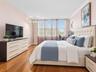 Room interior featuring wood-finish flooring, crown molding, and large window banks with horizontal blinds