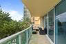 Covered balcony featuring stone flooring, a curved architectural design, and glass-paneled railings