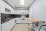 Kitchen featuring white cabinetry, dark stone-finish countertops, tile flooring, integrated appliances, and a mounted drop-leaf table
