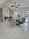 Floor-to-ceiling stone fireplace surround, polished large-format tile flooring, modern multi-arm chandelier, and sliding glass doors with access to an