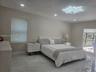 Polished stone-finish tile flooring, modern starburst ceiling fixture, recessed lighting, and dual windows with integrated shades