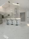 Kitchen featuring vaulted ceilings, skylights, white cabinetry, a center island with solid surfacing, and a stone-tiled backsplash with a stainless st