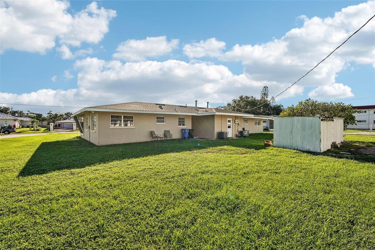 Back of duplex, shared laundry / utility room in center, plus two storage sheds. Oversized lot with a third of an acre!