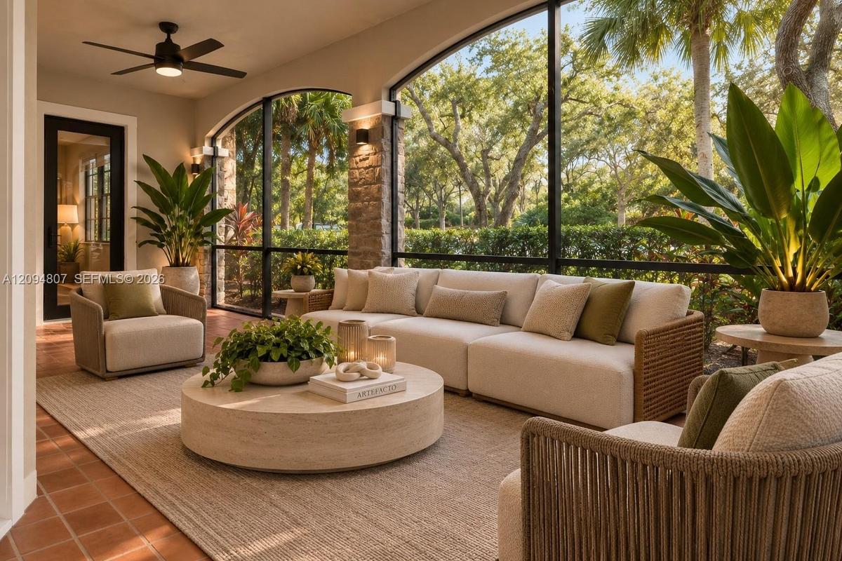 Screened-in outdoor living space featuring arched openings, stacked stone columns, tile flooring, and an integrated ceiling fan