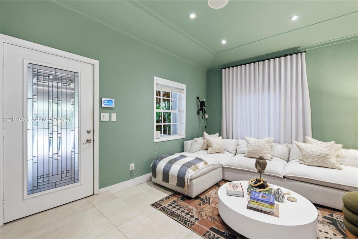 Entry area featuring a glass-inset door with geometric detailing, recessed ceiling lighting, tray ceiling architecture, large-format tile flooring, an