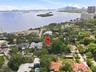 Aerial perspective of a coastal residential lot featuring mature tree canopy, significant landscaping, and proximity to the waterfront
