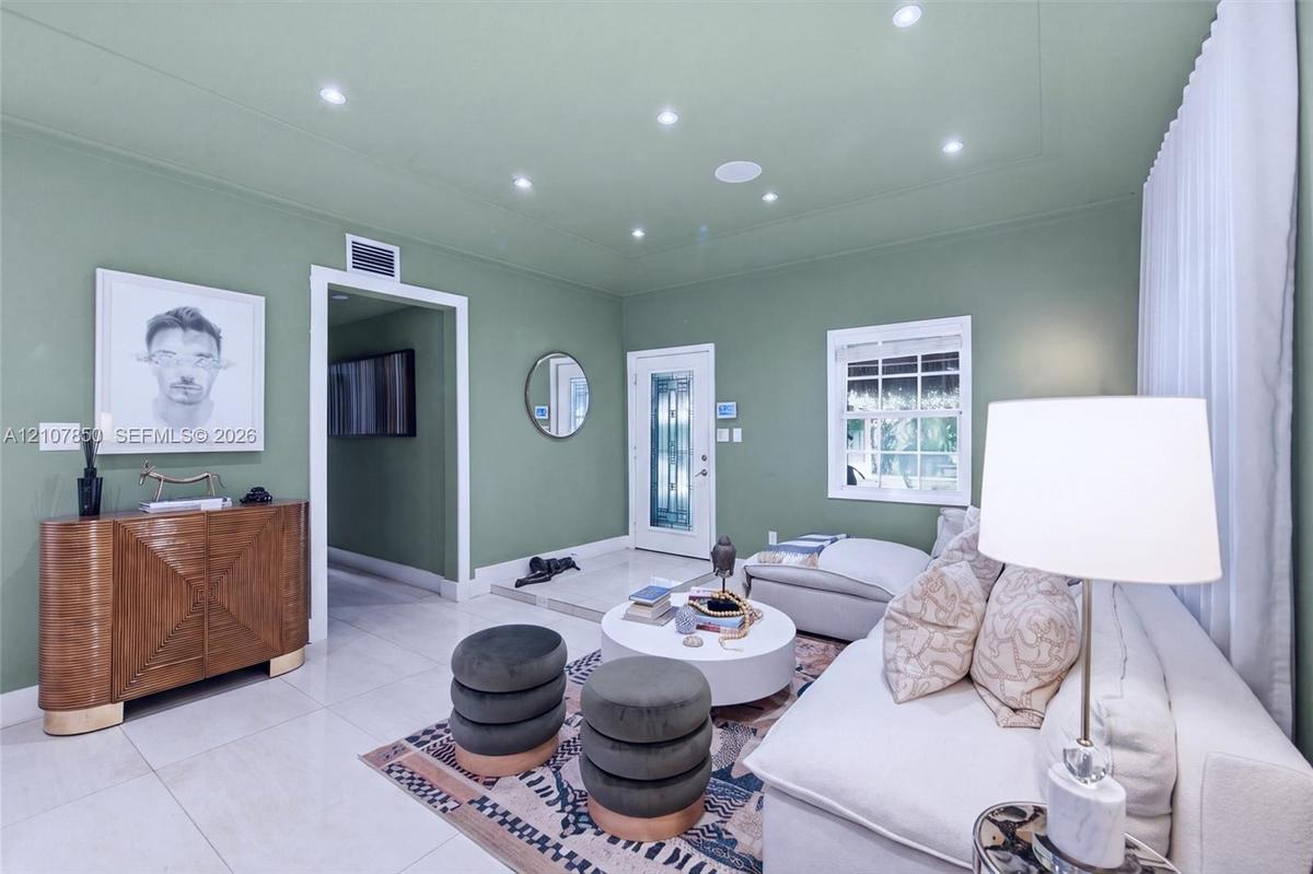 Living area featuring polished tile flooring, recessed ceiling lighting, a glass-paneled entry door, and crisp white trim