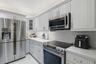 Kitchen featuring white shaker-style cabinetry, stainless steel appliances, white quartz countertops, and a subway tile backsplash
