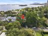 Aerial perspective of a property featuring mature tropical landscaping, a multi-car driveway with paved hardscaping, and proximity to the waterfront